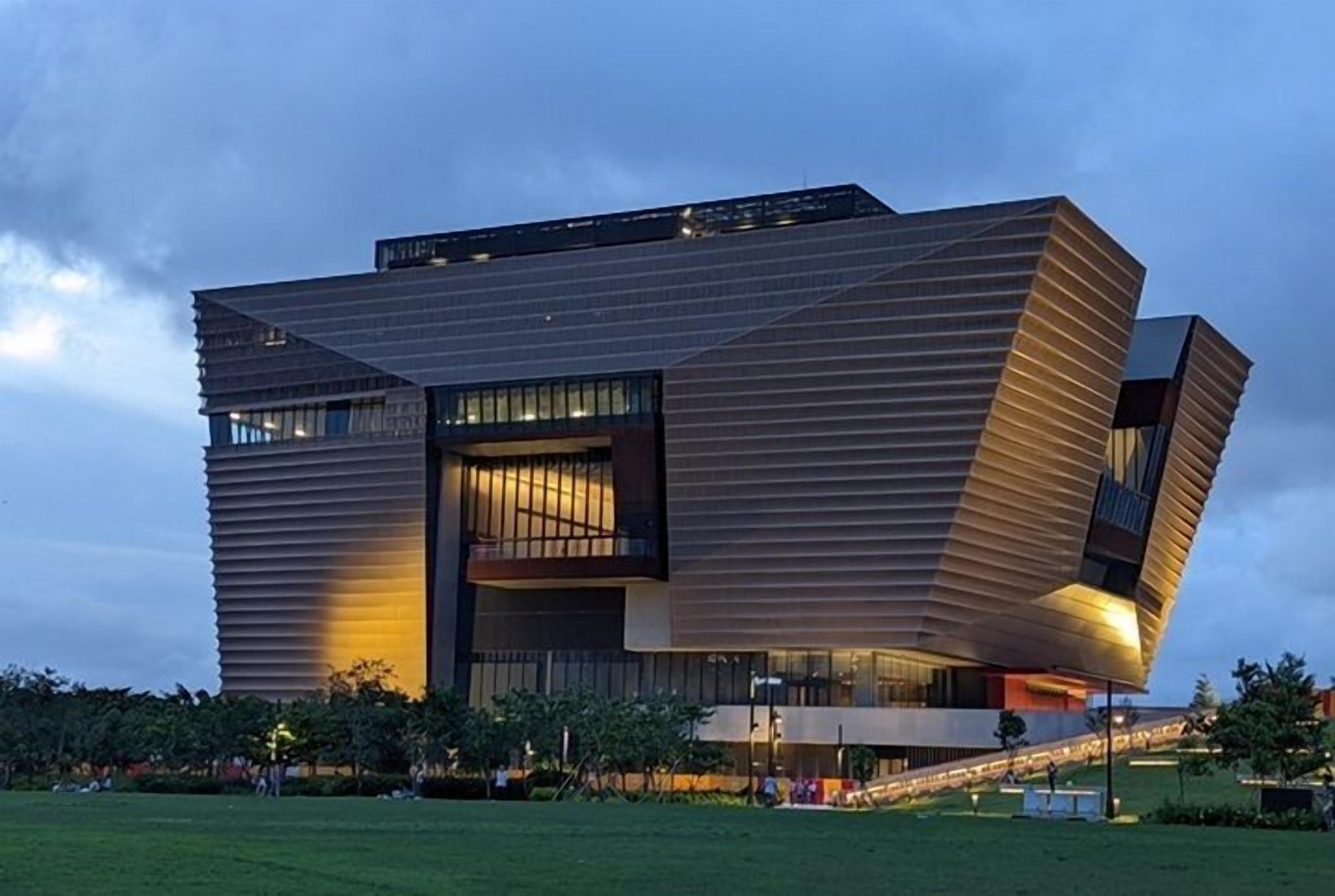 A modern building with a unique angular design, featuring multiple levels and large windows.