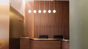 Un mostrador de recepción con dos computadoras Lenovo, un panel de pared de madera y una alfombra púrpura.