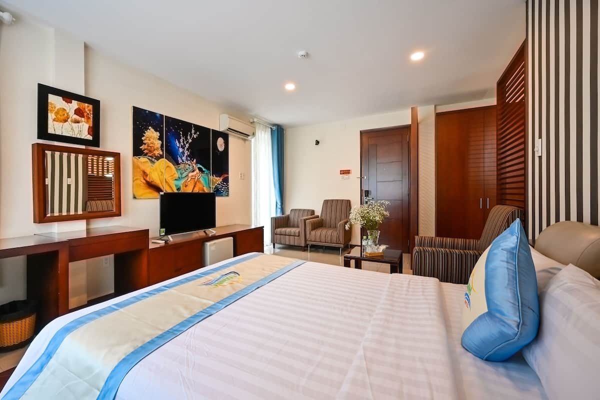 Hotelkamer met een groot bed, een bureau met een flatscreen televisie, een stoel, een kledingkast en kunst aan de muur.