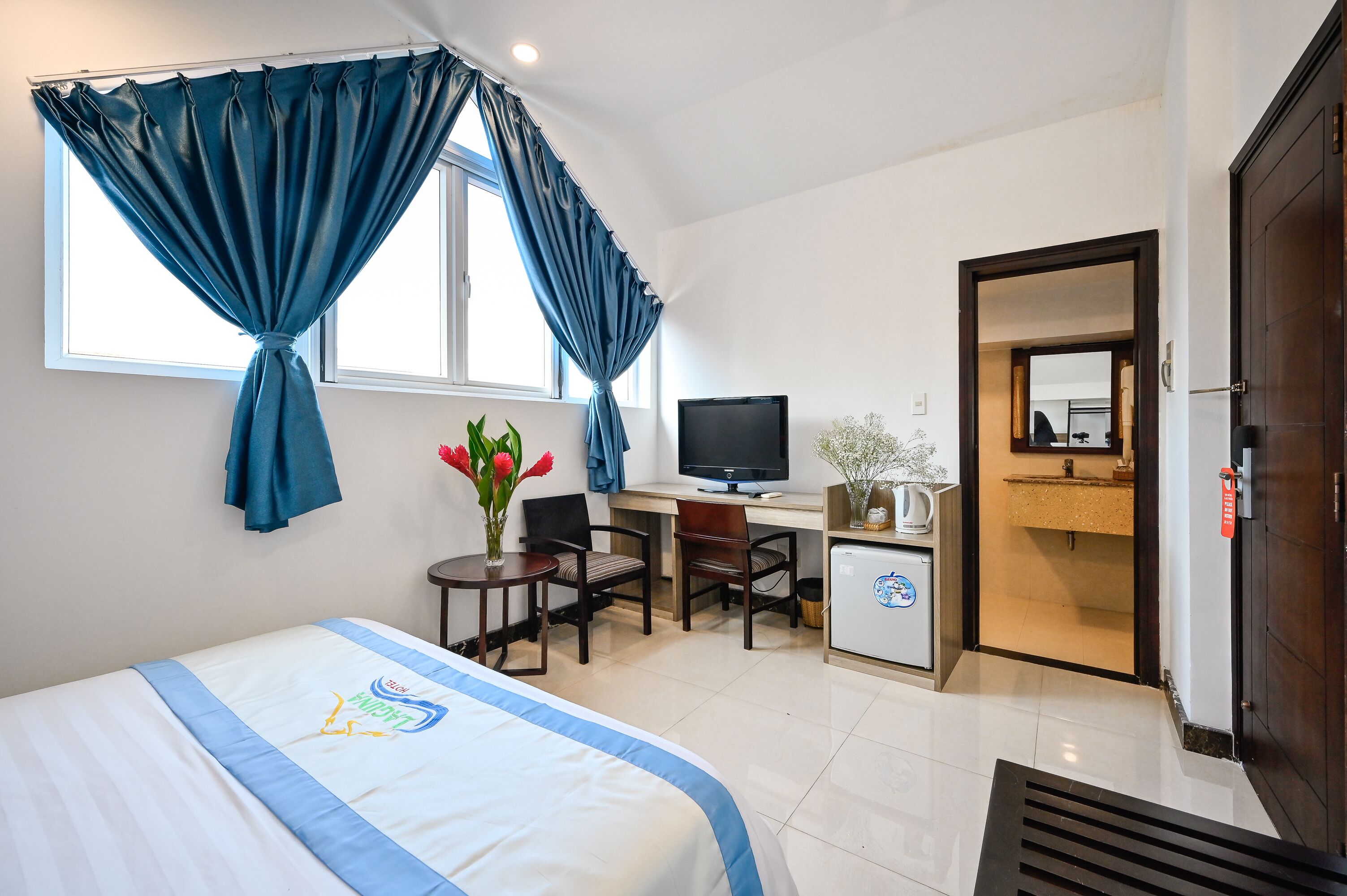 Une chambre d’hôtel équipée d’un lit, d’un bureau, d’une télévision et d’une petite kitchenette.