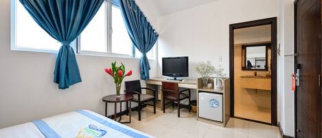 Une chambre d’hôtel équipée d’un lit, d’un bureau, d’une télévision et d’une petite kitchenette.