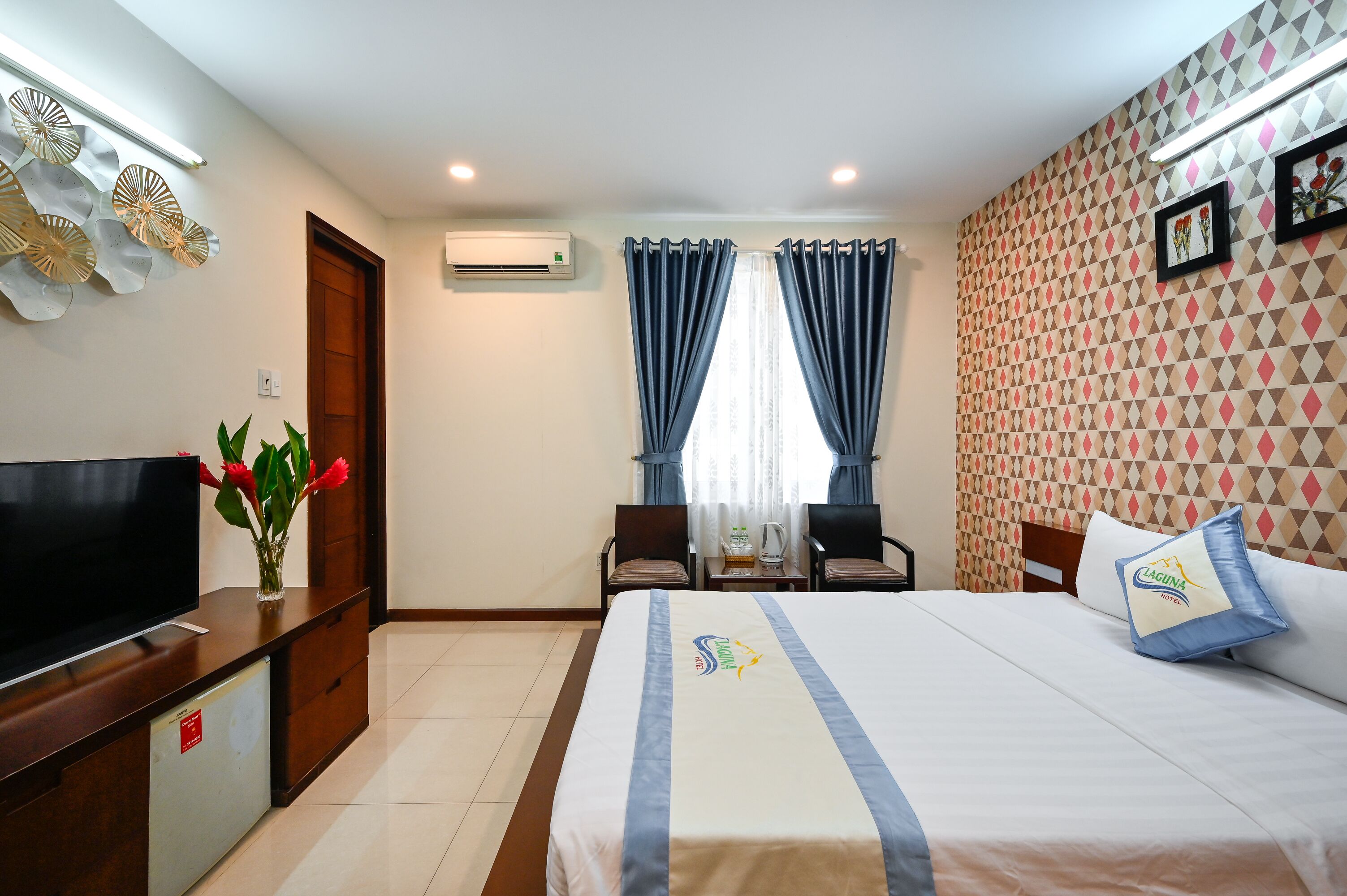 A hotel room with a bed, a TV, a desk, and a chair.