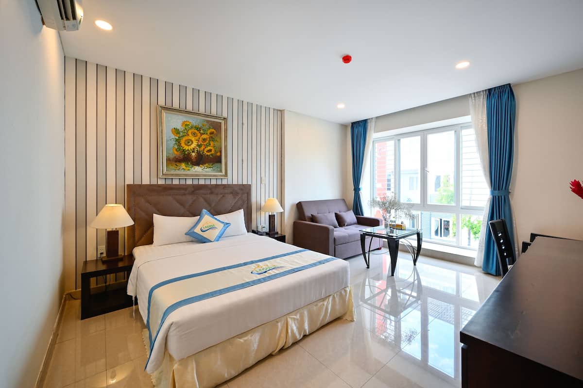 Een hotelkamer met een groot bed, een bank, een bijzettafeltje en een bureau.