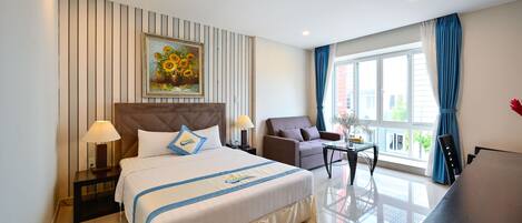 Una habitación de hotel con una cama grande, un sofá, una mesita y un escritorio.