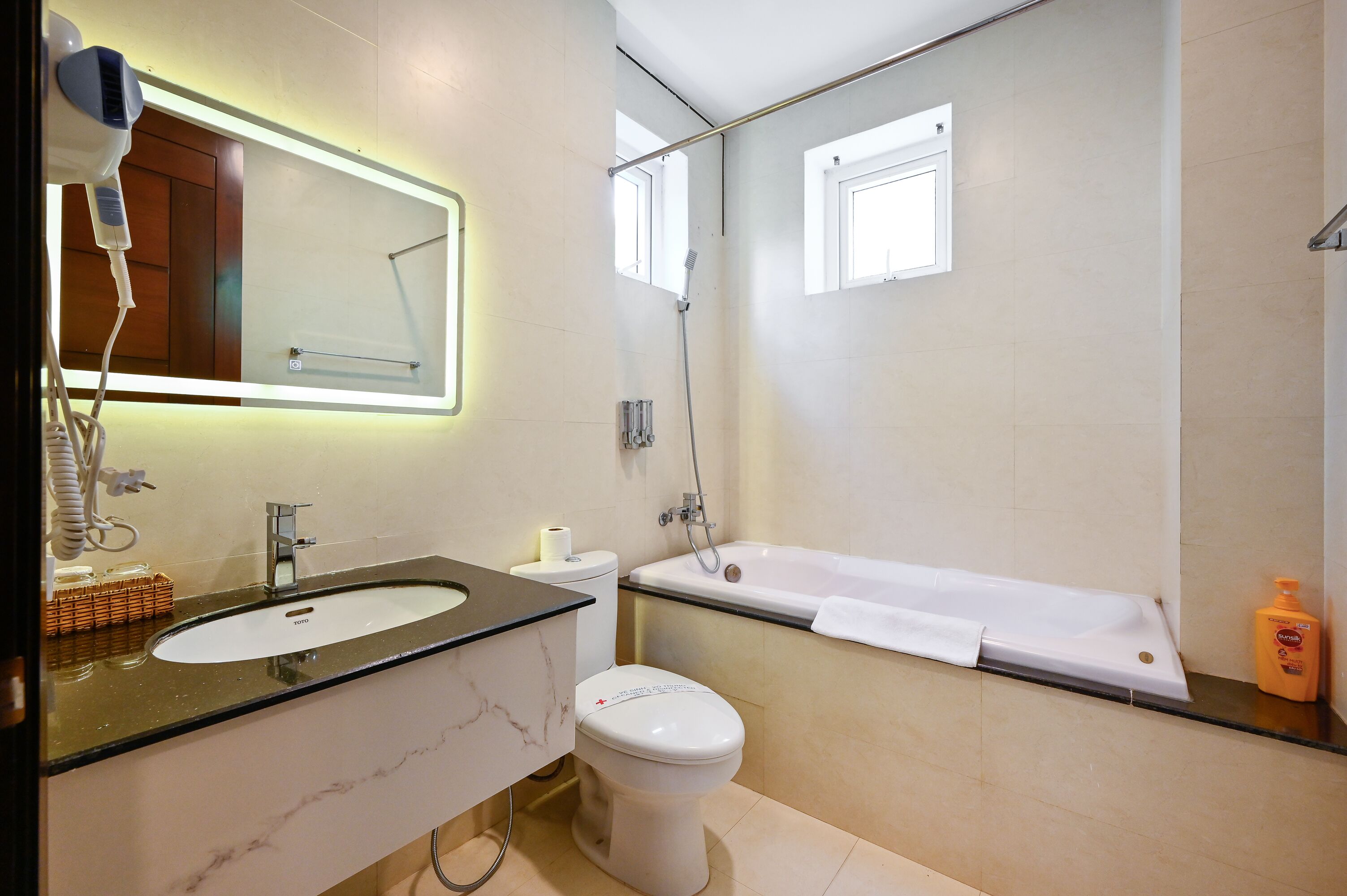 Un baño moderno con lavamanos de mármol, inodoro, bañera y secador de pelo en la encimera.