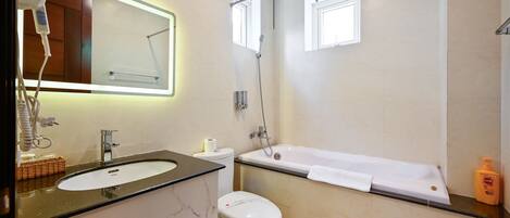 Un baño moderno con lavamanos de mármol, inodoro, bañera y secador de pelo en la encimera.