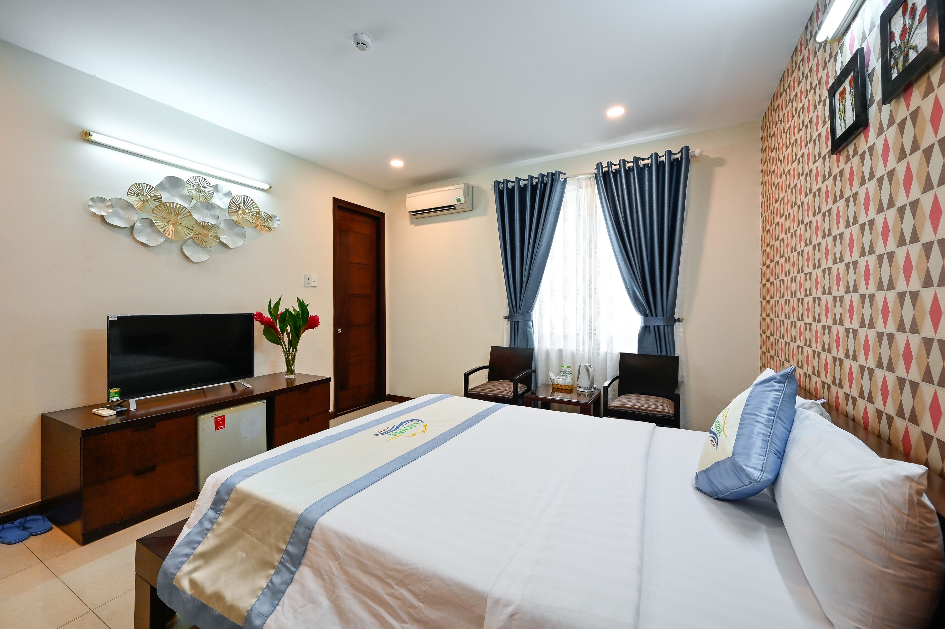A hotel room with a bed, a TV, a desk, and a chair.