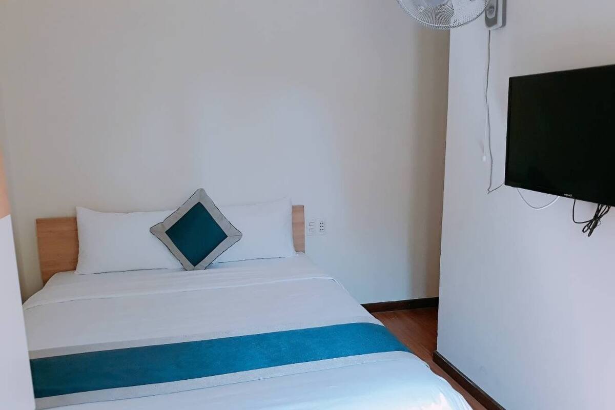 A hotel room with a bed, a wall-mounted TV, and a ceiling fan.