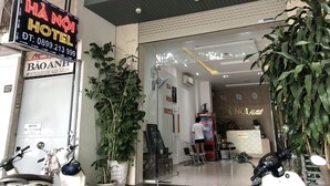 Ein Hotel Eingangsbereich mit einer Rezeption, einem Schild mit der Aufschrift 'HÀ NỘI HOTEL' und einem Schild mit 'BÀO ANH'.