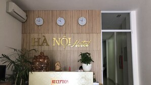 Eine Rezeption mit Uhren, einer Wandpaneelausstattung aus Holz und einem Schild mit der Aufschrift 'HA NOI Hotel'.