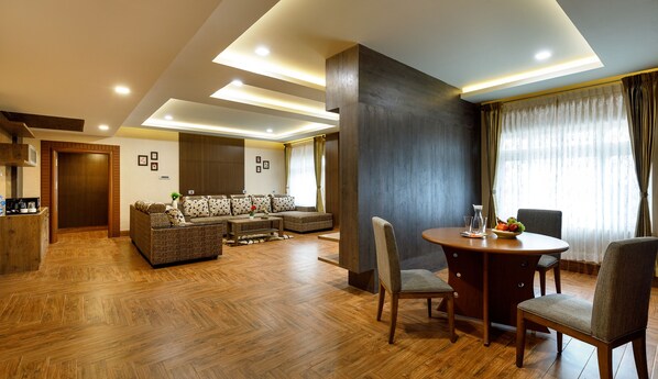 A modern living room with a sofa set, a dining table with chairs, and a kitchen area.
