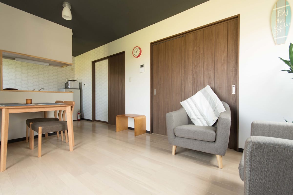 A modern living room with a dining area, a sofa, a small table, and a wooden cabinet.