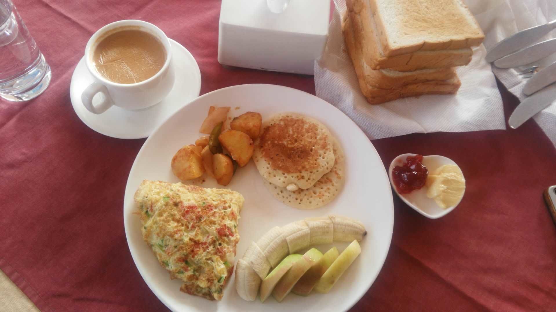 A breakfast plate with toast, pancakes, eggs, potatoes, and a banana.