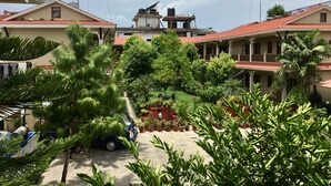 Une cour intérieure agrémentée de plantes en pot et où est garée une voiture.