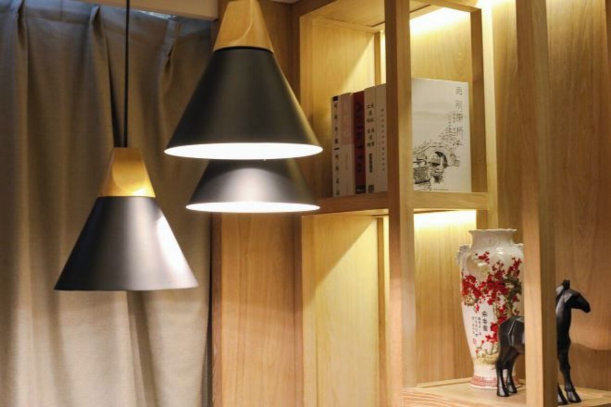 Una habitación con una estantería de madera, un jarrón decorativo y dos lámparas colgantes.