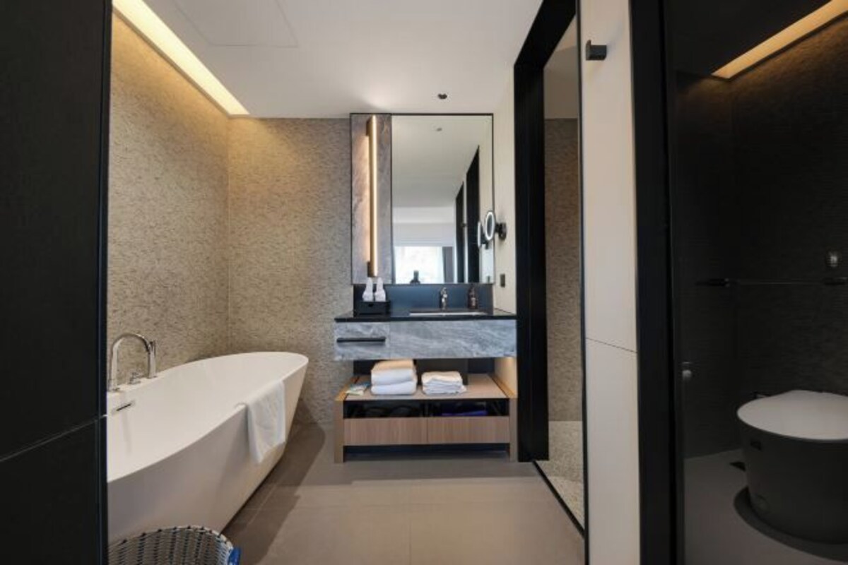 Un baño moderno con una bañera independiente, un tocador con espejo y un inodoro.
