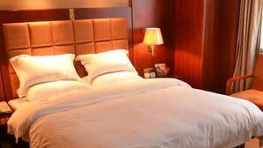 Habitaci ón de hotel con una cama grande, una mesita de noche, una lámpara y un cabecero de madera.