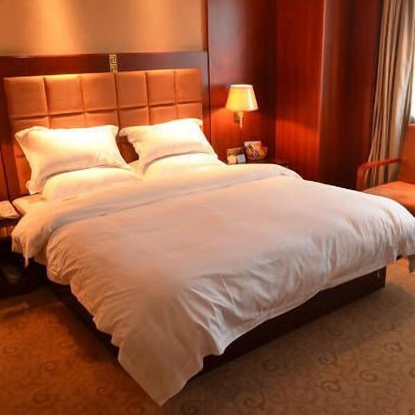 Habitación de hotel con una cama grande, una mesita de noche, una lámpara y un cabecero de madera.
