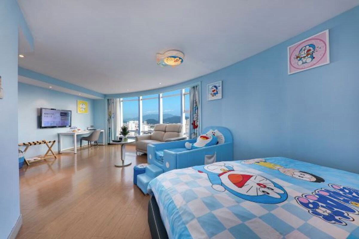 A modern bedroom with a large bed, a desk, and a view of the city.