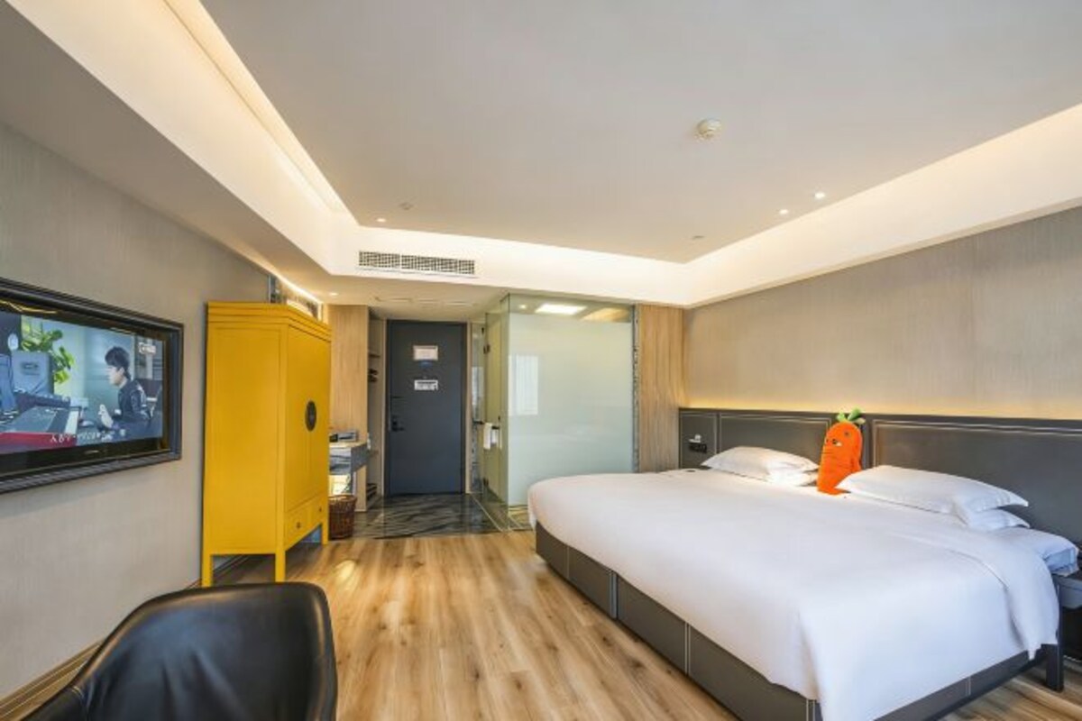 Una habitación de hotel con cama, televisión, escritorio y armario.