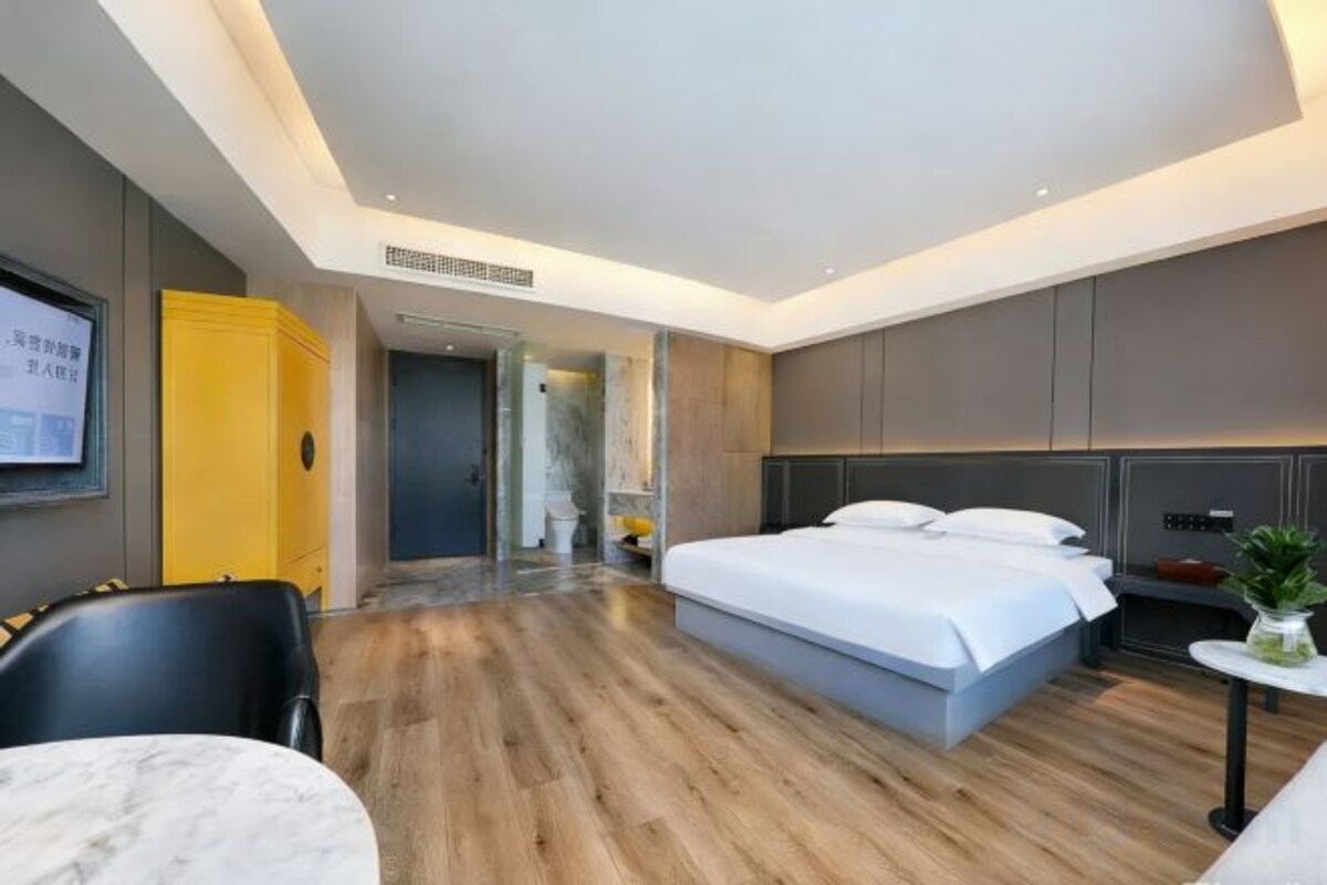 A modern hotel room with a large bed, a desk, and a seating area.