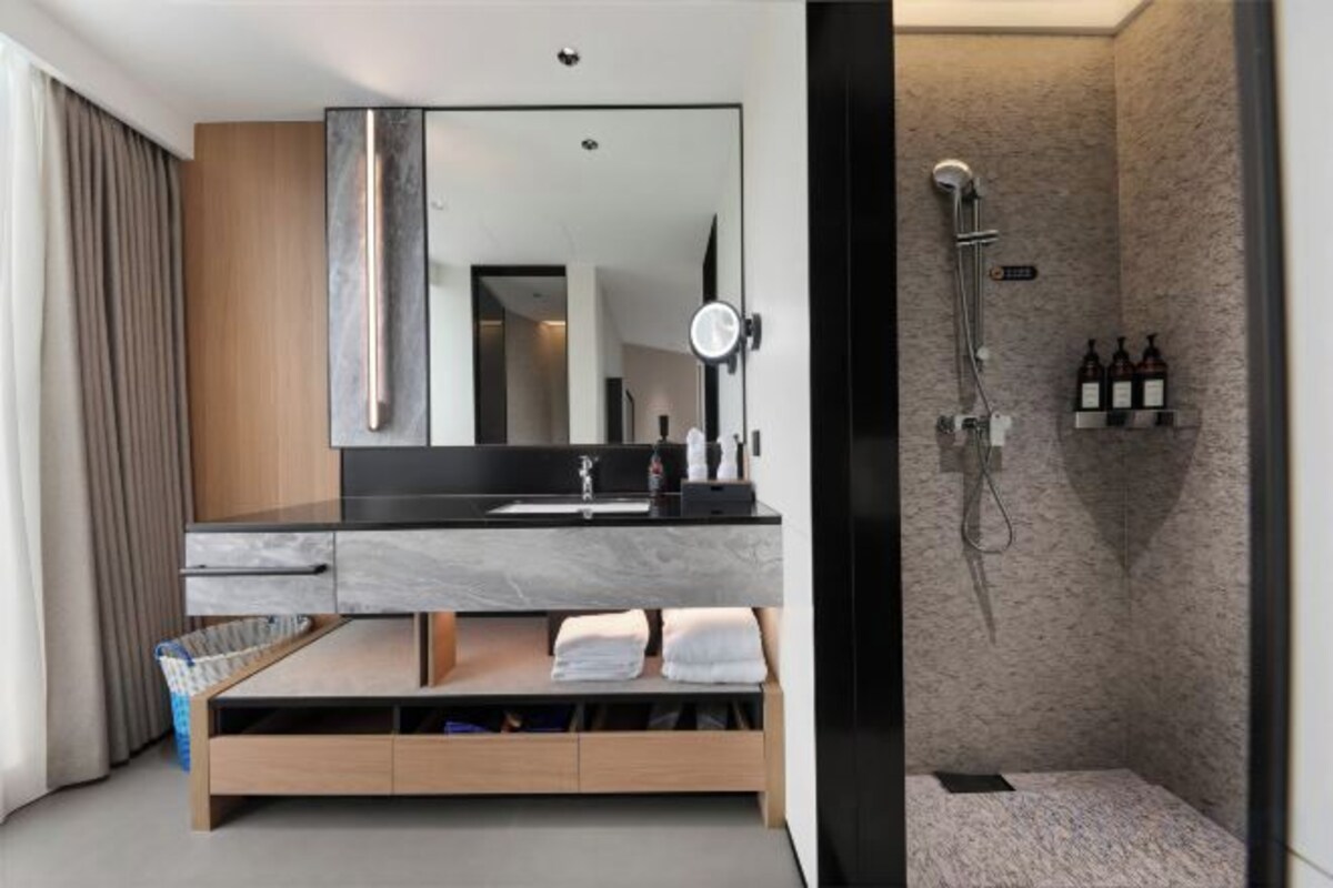 A modern bathroom with a large mirror, a sink, and a shower area.