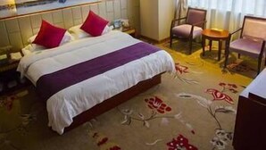 Una habitación de hotel con cama, una silla, un escritorio y un cuadro en la pared.