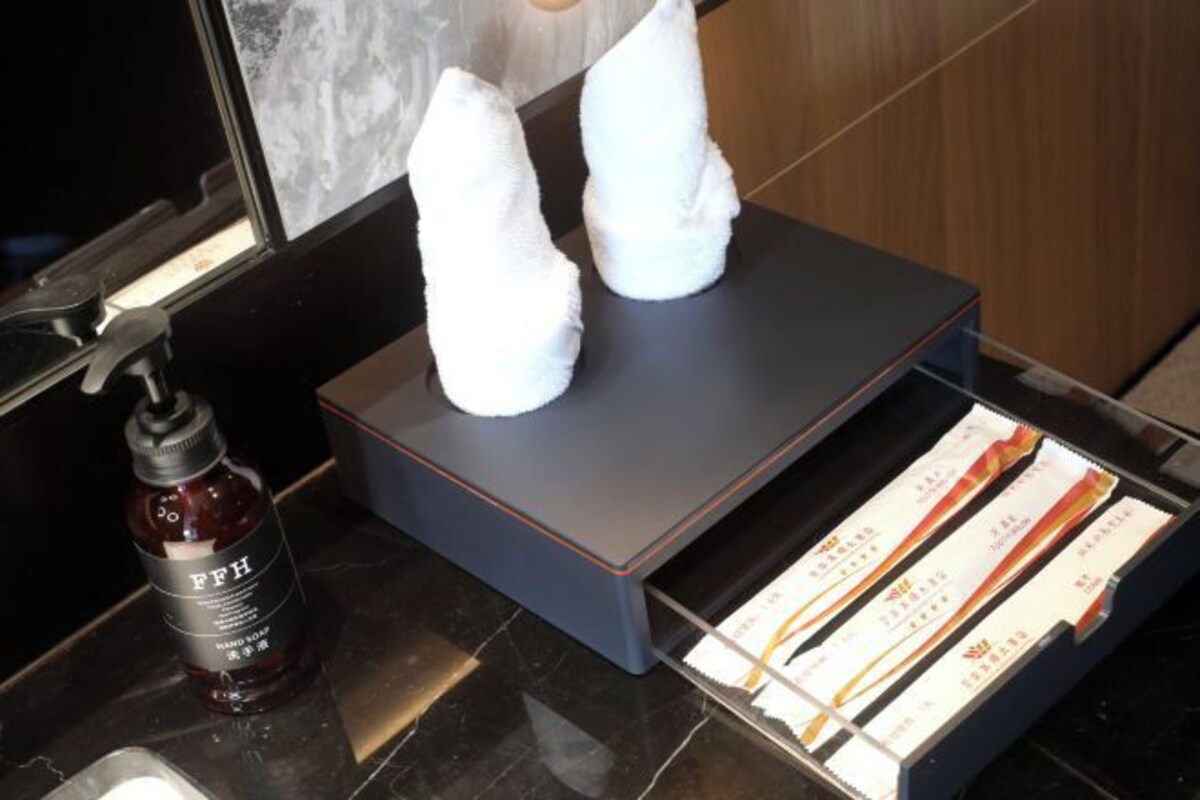 Uma casa de banho com dispensador de toalhas, um frasco de sabonete líquido e uma caixa de lenços de papel.