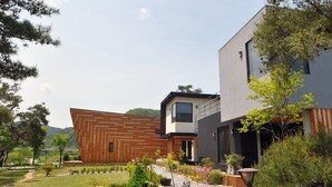 A modern two-story house with a wooden facade and a grey upper level.