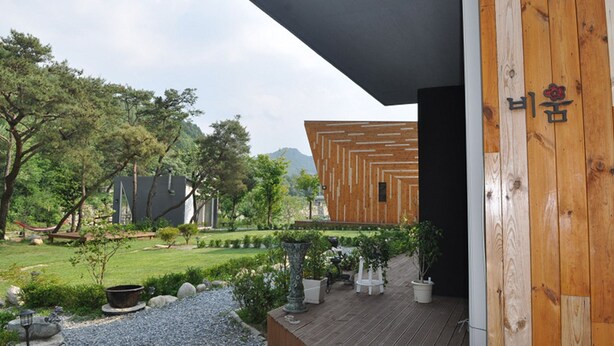 A modern building with a wooden exterior and a garden area with potted plants and a small pond.