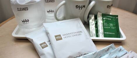 Una bandeja con artículos de tocador de hotel, incluyendo bolsas con la etiqueta “WHG Hotels”, una bandeja de té verde y tazas blancas con el logotipo “WHG”.