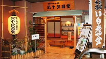 Un restaurant japonais traditionnel, avec une façade en bois, une enseigne portant des caractères japonais et un panneau affichant le menu à l’extérieur.