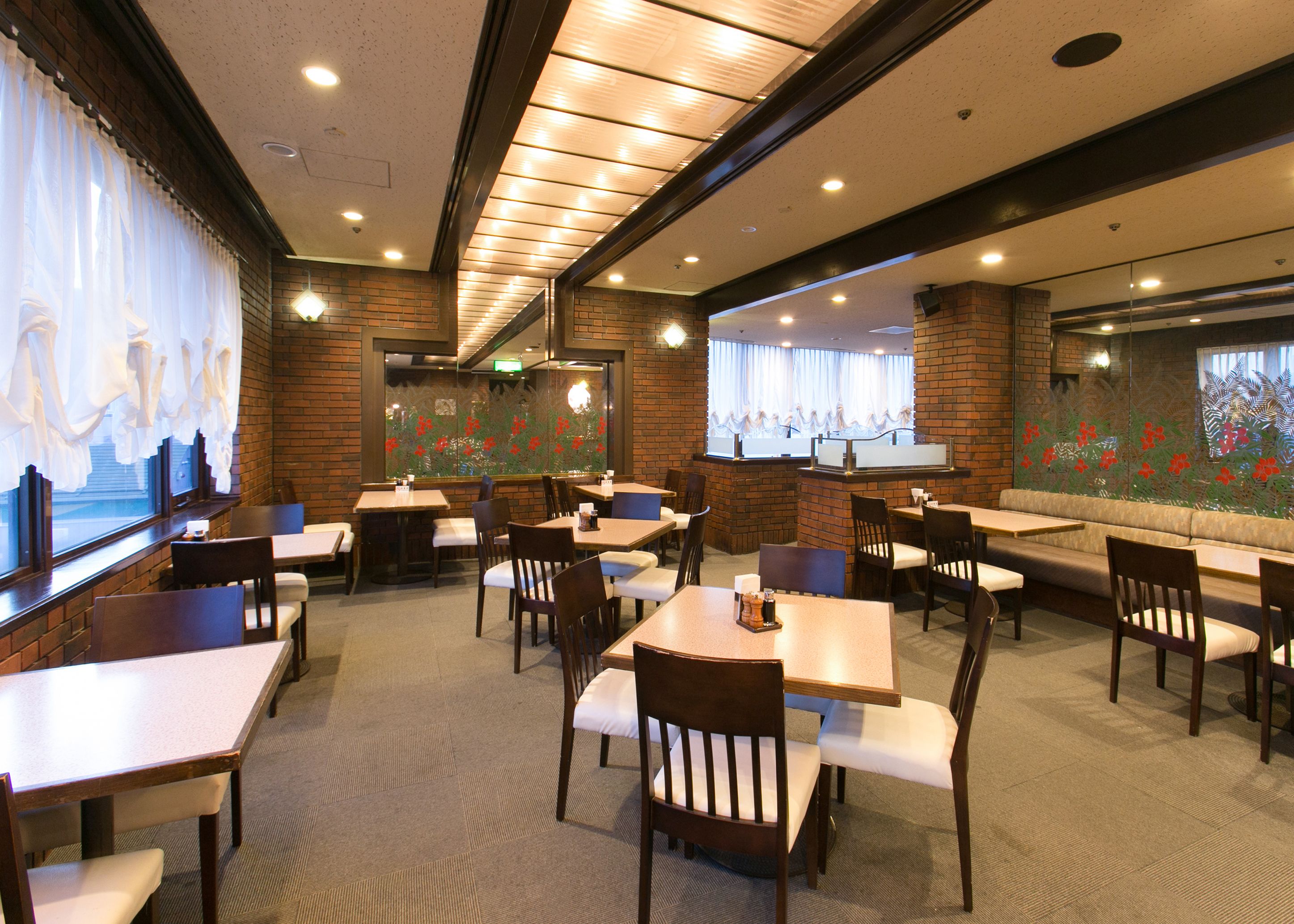 A restaurant with brick walls, multiple seating areas, and a view of the street through large windows.