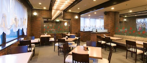 A restaurant with brick walls, multiple seating areas, and a view of the street through large windows.