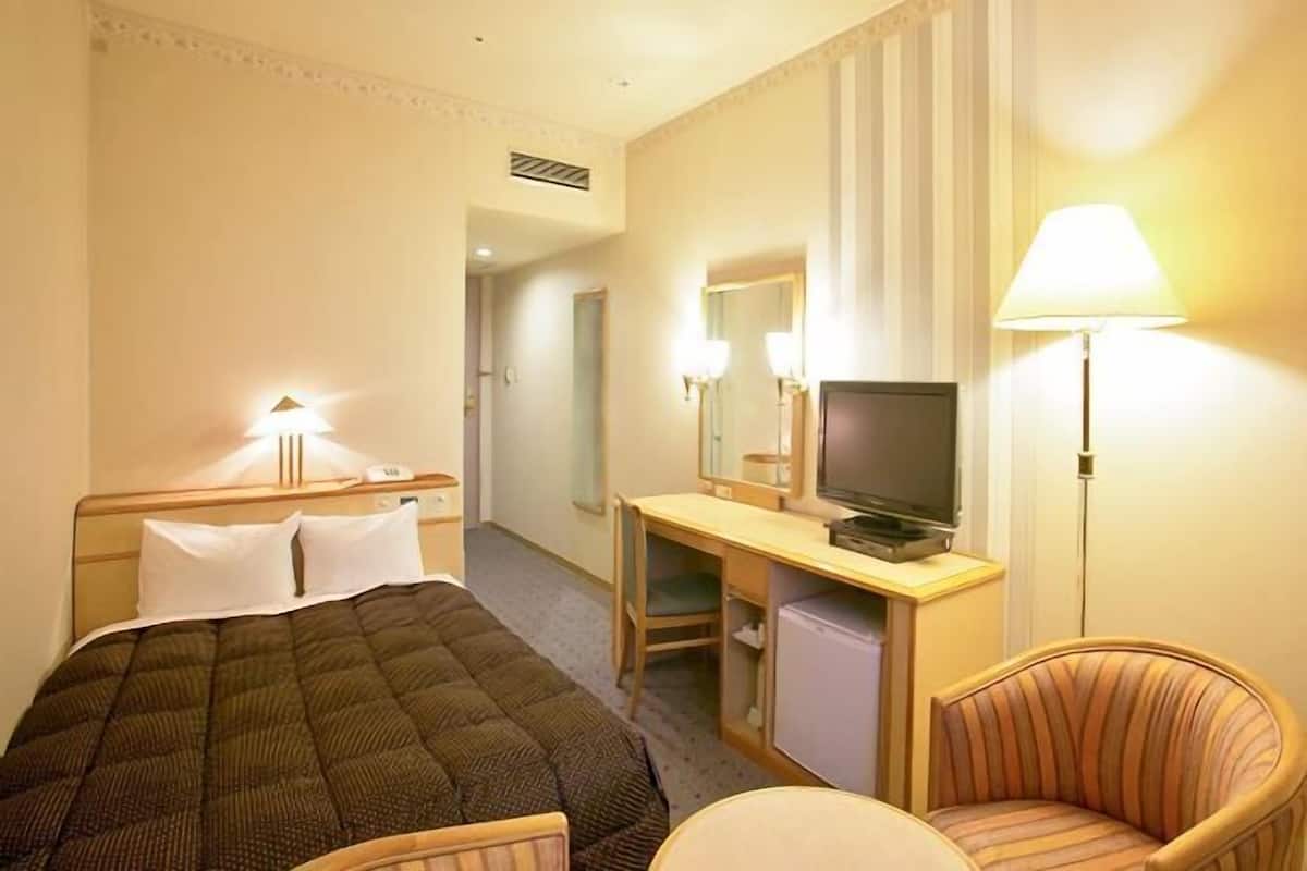 Une chambre d’hôtel équipée d’un lit, d’un bureau, d’une télévision, d’une chaise et de lampes.