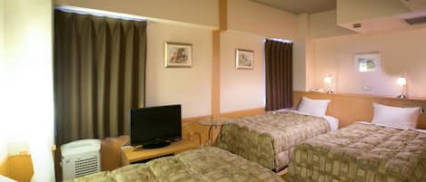 A hotel room with two beds, a television, a desk, and a window with curtains.
