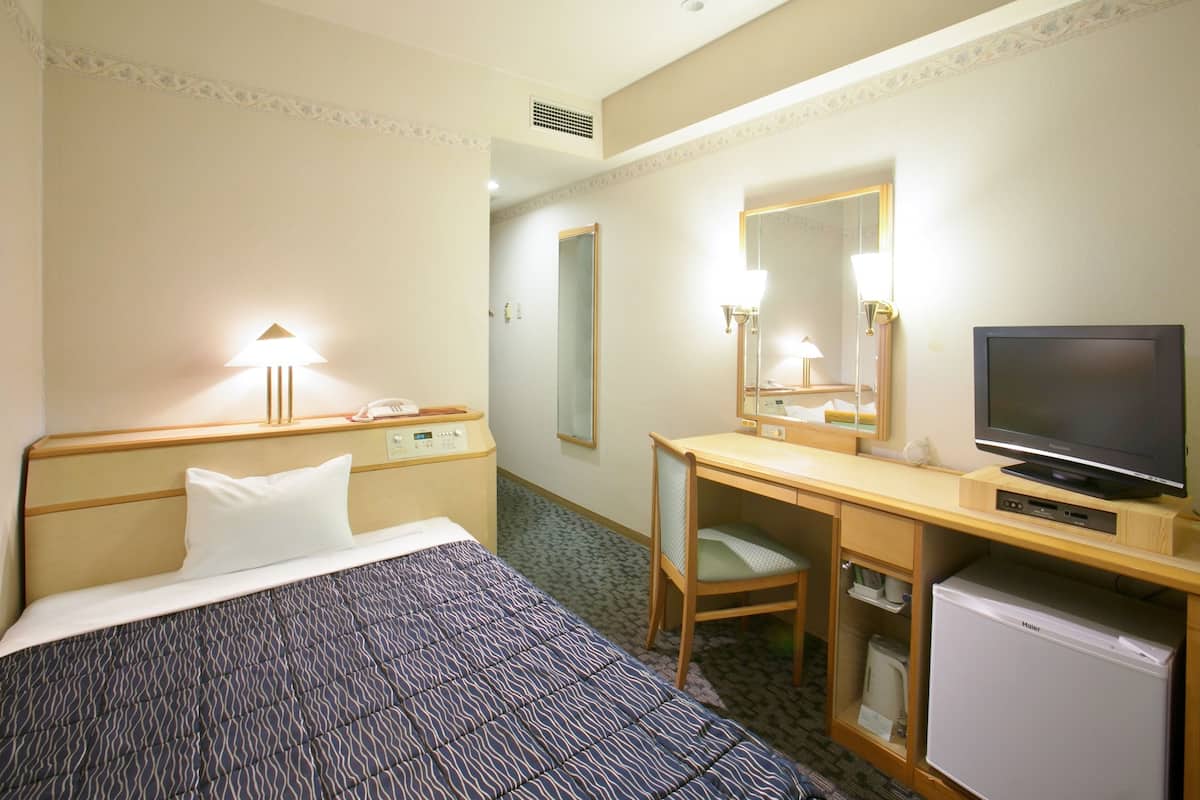 Une chambre d’hôtel comprenant un lit, un bureau avec une télévision, un réfrigérateur et une chaise.