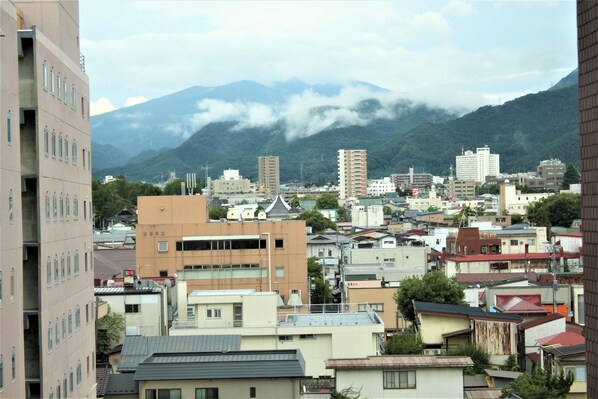 Un paisaje urbano con edificios residenciales y comerciales, una cadena montañosa al fondo y un cielo nublado.