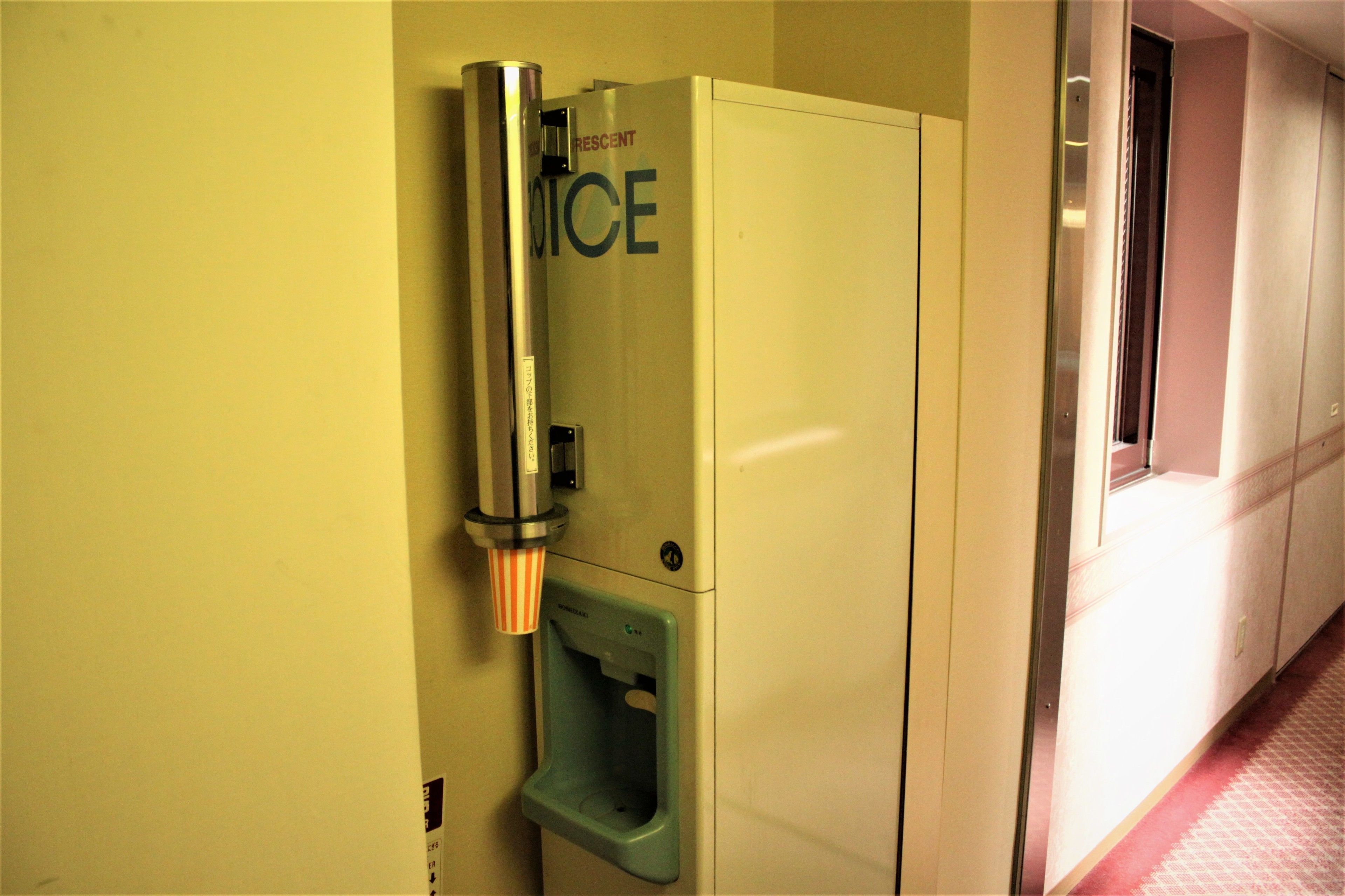 Eine Toilette mit einem Wasserspender mit der Aufschrift "RESCENT ICE" und einer grünen Mülltonne.
