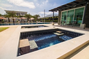 A swimming pool area with two separate pools, lounge chairs, and umbrellas. - Luxury 5br Pool Villa and Sport Center (Sattahip)