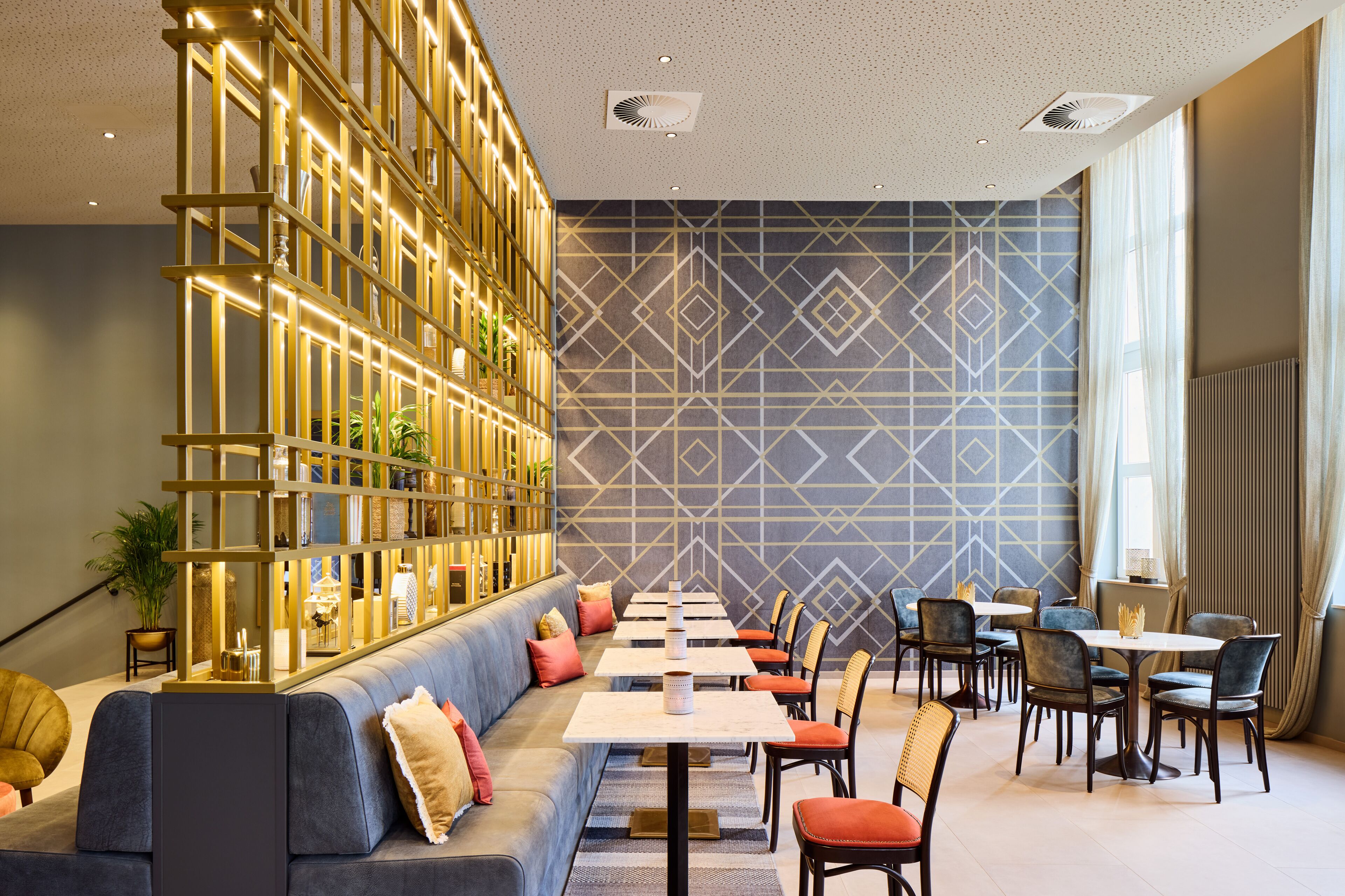 Een modern restaurant met een lange toonbank, comfortabele zitplaatsen en een decoratieve wand met geometrische patronen.
