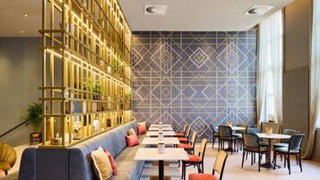 Een modern restaurant met een lange toonbank, comfortabele zitplaatsen en een decoratieve wand met geometrische patronen.