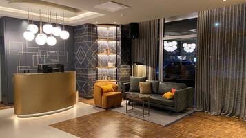 A modern hotel lobby with a reception desk, a sofa, a coffee table, and a bookshelf.