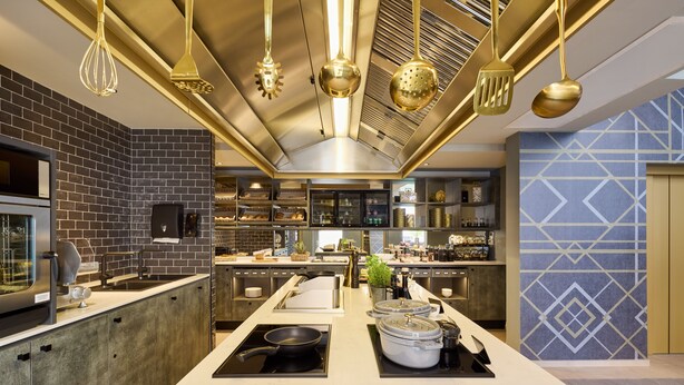 A modern kitchen with a central island, stainless steel appliances, and a brick backsplash. - Postboutique Hotel (Wuppertal)