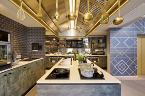 A modern kitchen with a central island, stainless steel appliances, and a brick backsplash. - Postboutique Hotel (Wuppertal)