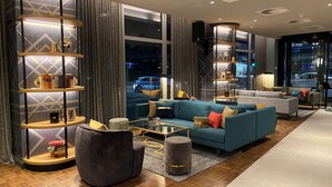 A modern living room with a sofa, armchairs, a coffee table, and a bookshelf. - Postboutique Hotel (Wuppertal)