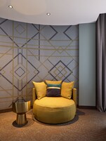 Un sofá moderno y circular con un pared detrás decorada con un estampado geométrico.