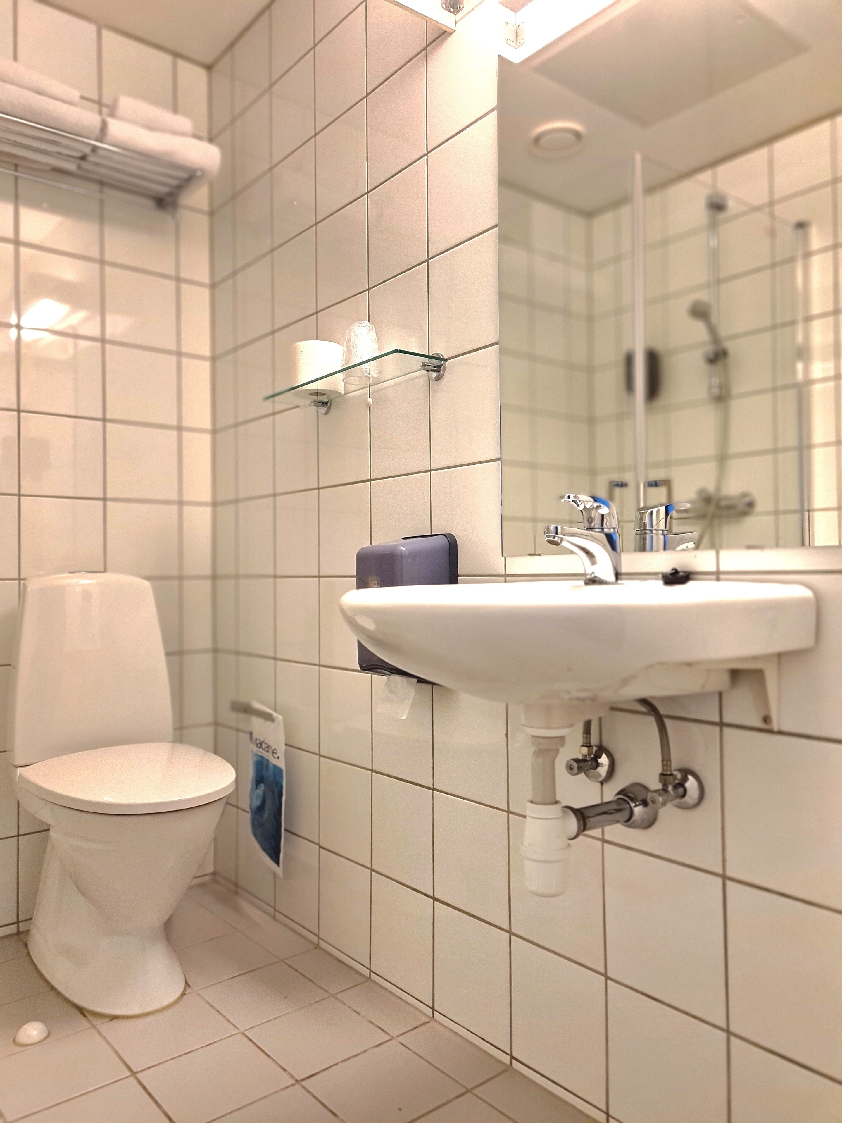 Un baño con inodoro blanco, lavabo con espejo y cabina de ducha de cristal.