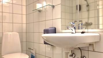 A bathroom with a white toilet, a sink with a mirror above it, and a glass shower enclosure.