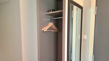 Un vestidor con espejo, perchero y puerta.